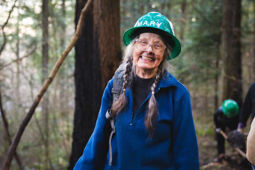 A woman in a green hard hat smiles for the camera.