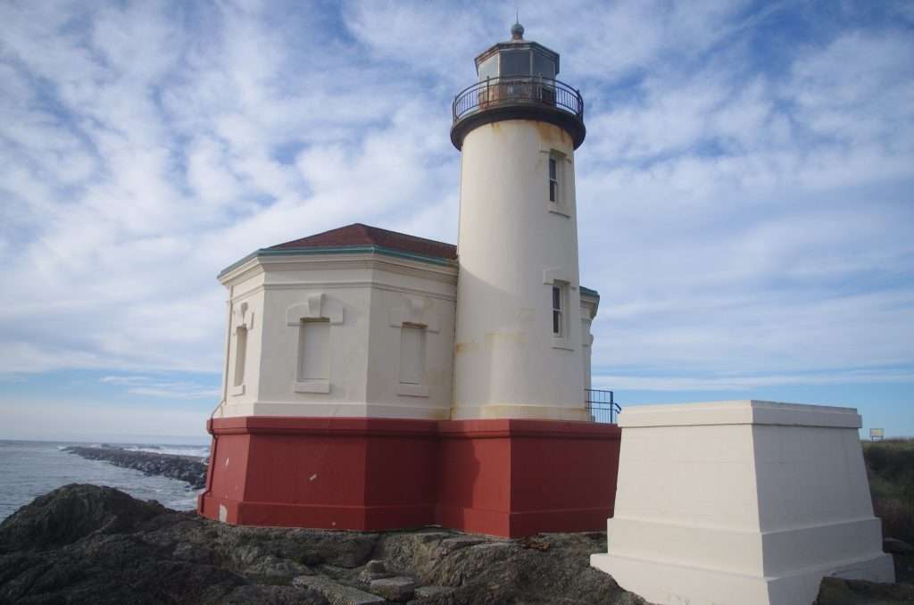 A white lighthouse with a red roof and red-painted foundation.