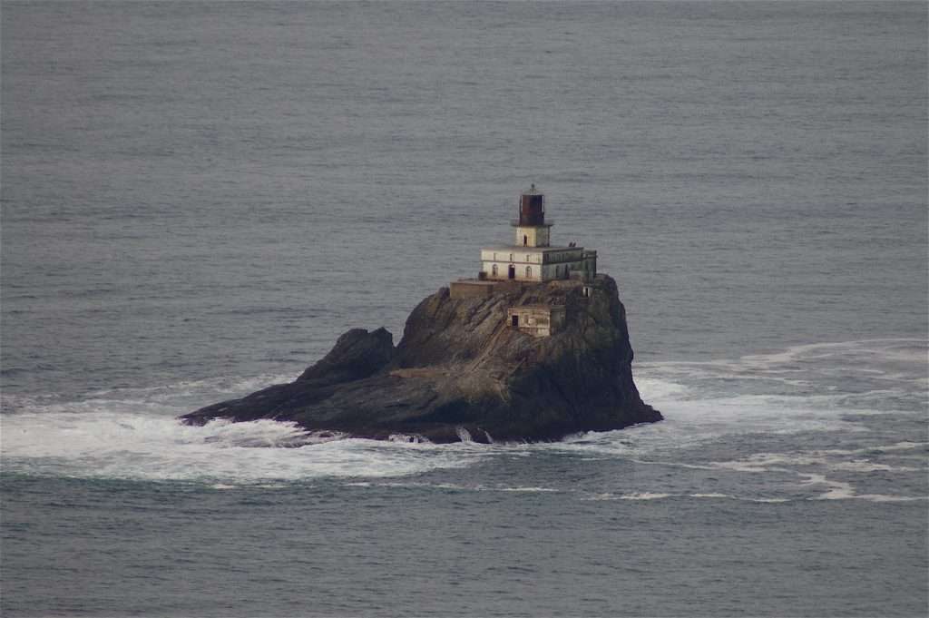 A small lighthouse on a rock in the ocean.