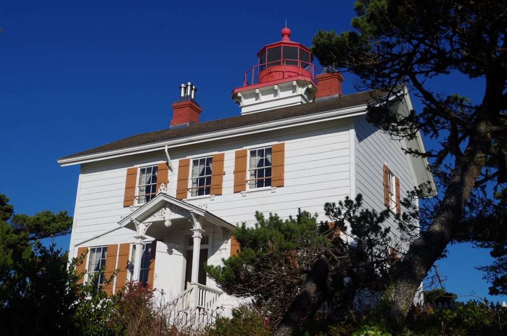 A white house topped by a red lighthouse tower on its roof.