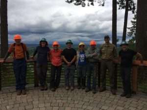Eight people stand together wearing hard hats with a view of the mountains behind them 